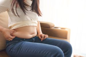 woman holding her own belly when sitting down sofa living room s