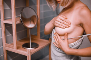 young woman standing front mirror checking her breast while self exam breast cancer awareness how i check breast concept
