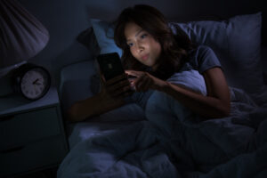 young woman using smartphone her bed night