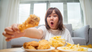 chubby asian woman express happiness when eating fried chicken fries potato snacks