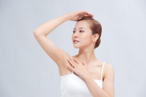 beautiful young asian woman lifting hands up show off clean hygienic armpits underarms white background