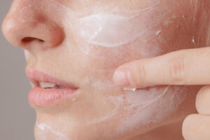 young woman applying moisturizer