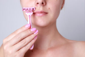 closeup woman shaving her face with razor face epilation laser epilation upper lip female